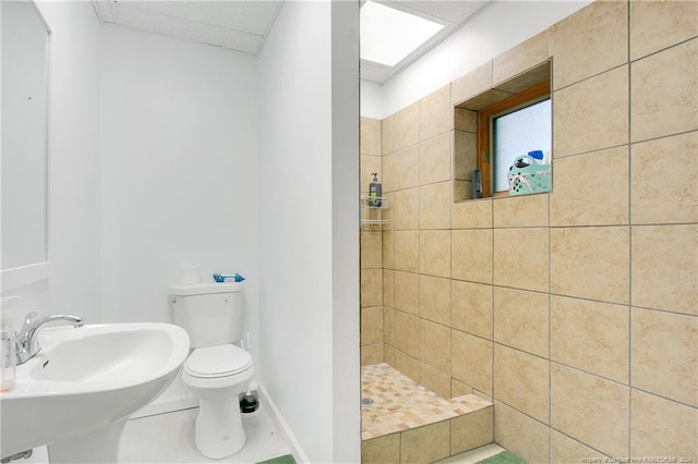 bathroom featuring sink, tile patterned flooring, toilet, and a tile shower