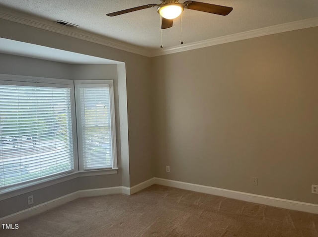 carpeted spare room with a textured ceiling, ornamental molding, and ceiling fan