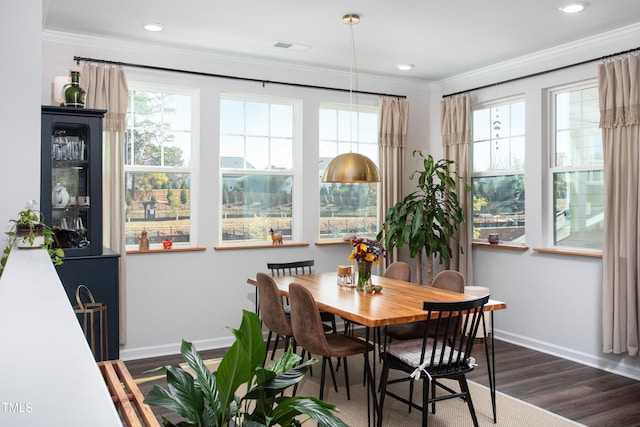 dining room with dark wood-type flooring, a healthy amount of sunlight, and crown molding