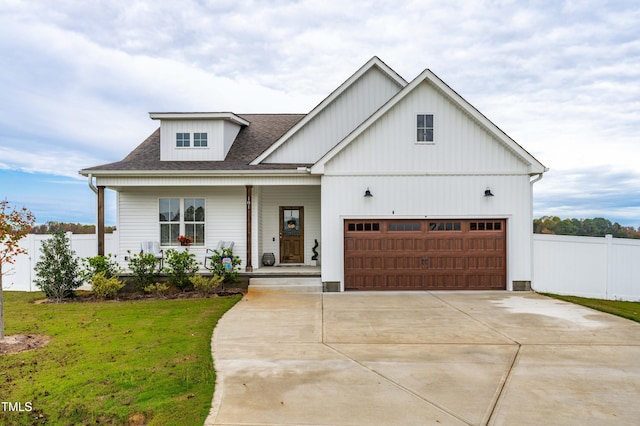 modern farmhouse featuring covered porch, a garage, and a front yard