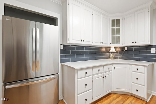 kitchen featuring white cabinets, decorative backsplash, stainless steel fridge, and light hardwood / wood-style flooring