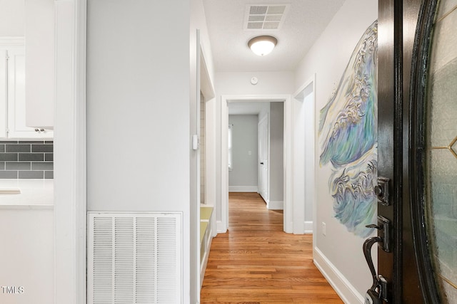 hall with a textured ceiling and light hardwood / wood-style floors