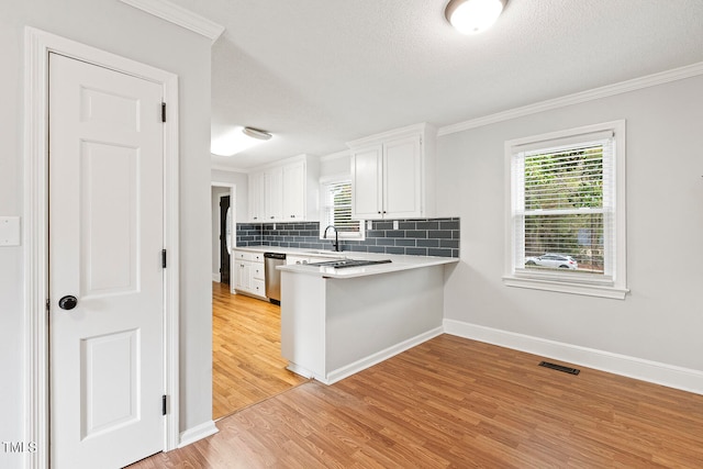 kitchen featuring tasteful backsplash, stainless steel dishwasher, sink, light hardwood / wood-style flooring, and white cabinets