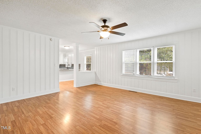 unfurnished room featuring a textured ceiling, light hardwood / wood-style flooring, and ceiling fan