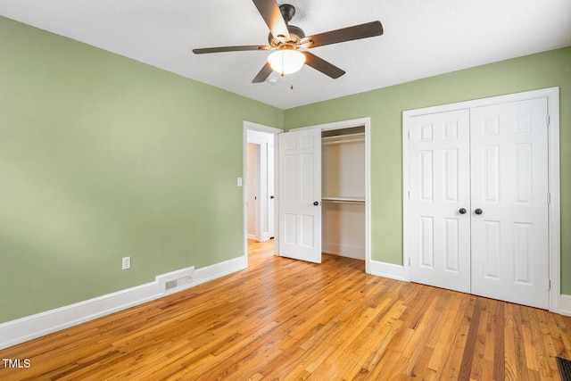 unfurnished bedroom with light wood-type flooring, two closets, and ceiling fan