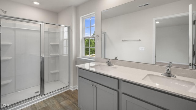 bathroom with hardwood / wood-style floors, a shower with shower door, plenty of natural light, and vanity