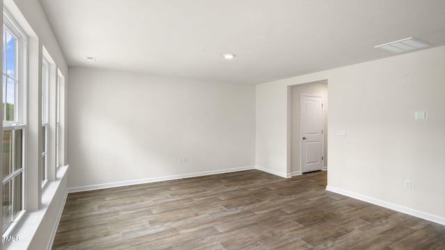 spare room featuring dark wood-type flooring and plenty of natural light