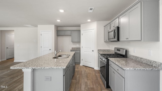 kitchen with sink, appliances with stainless steel finishes, a kitchen island with sink, gray cabinetry, and dark hardwood / wood-style flooring