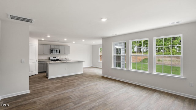 kitchen featuring stainless steel appliances, dark hardwood / wood-style floors, sink, and a kitchen island with sink