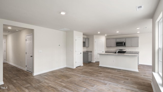 kitchen featuring stainless steel appliances, a center island with sink, sink, hardwood / wood-style floors, and gray cabinets