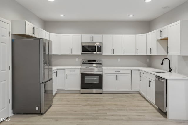 kitchen with white cabinets, light hardwood / wood-style floors, appliances with stainless steel finishes, and sink