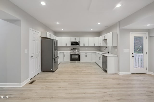 kitchen with white cabinets, stainless steel appliances, light hardwood / wood-style floors, and sink