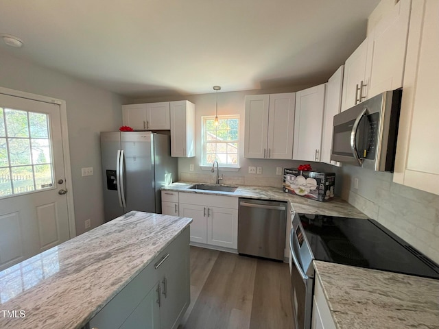 kitchen featuring sink, stainless steel appliances, hanging light fixtures, and white cabinets