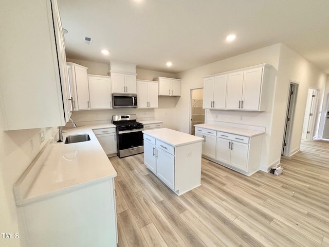 kitchen featuring a center island, sink, light hardwood / wood-style flooring, appliances with stainless steel finishes, and white cabinetry