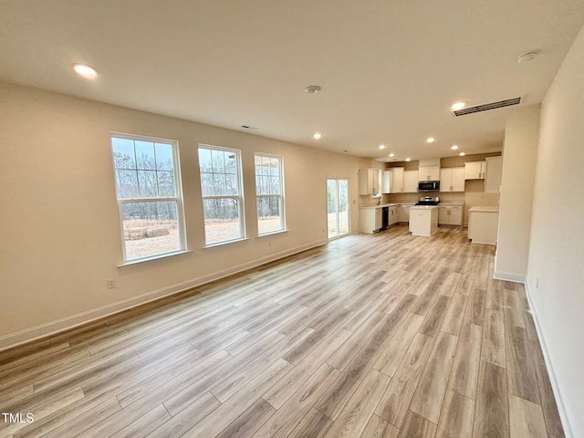 unfurnished living room with light hardwood / wood-style floors and a healthy amount of sunlight