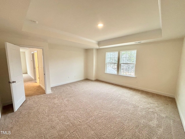 empty room with light colored carpet and a tray ceiling