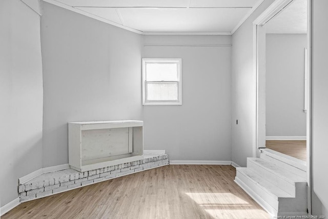 empty room with light wood-type flooring and crown molding