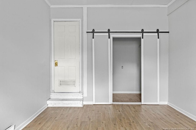 unfurnished bedroom with hardwood / wood-style flooring, a barn door, and a closet