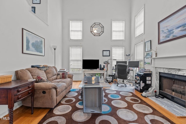 living room featuring a tile fireplace, a high ceiling, and hardwood / wood-style flooring