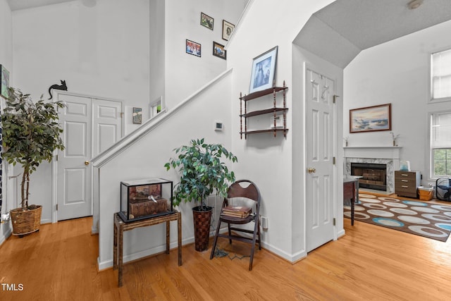 staircase featuring a fireplace, hardwood / wood-style floors, and high vaulted ceiling