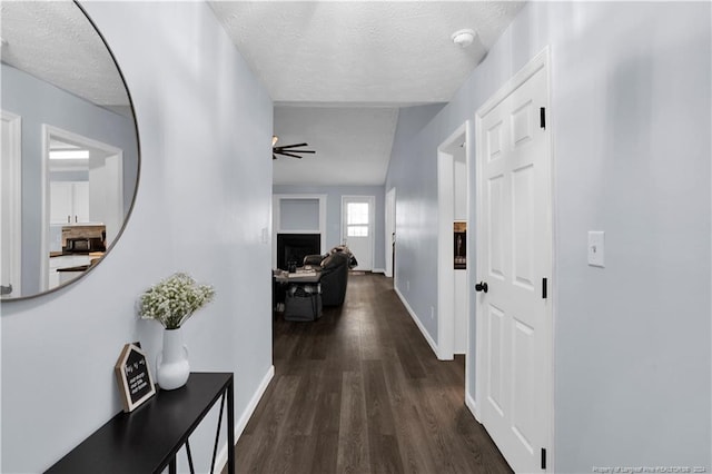 hallway with dark hardwood / wood-style flooring, lofted ceiling, and a textured ceiling