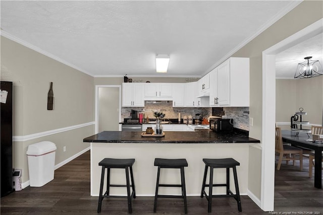 kitchen featuring white cabinetry, ornamental molding, dark hardwood / wood-style floors, and tasteful backsplash