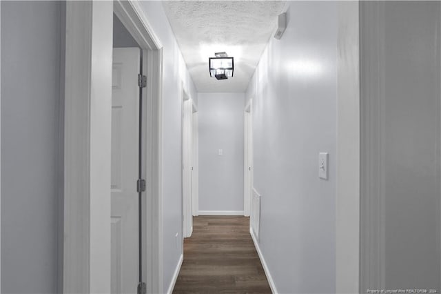 corridor with dark wood-type flooring and a textured ceiling