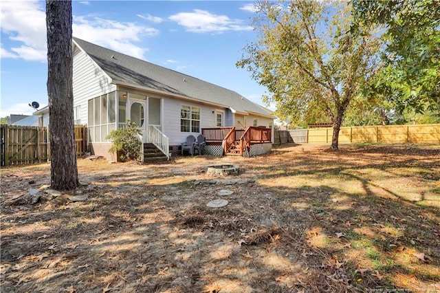 rear view of property featuring a wooden deck, a fenced backyard, and a sunroom