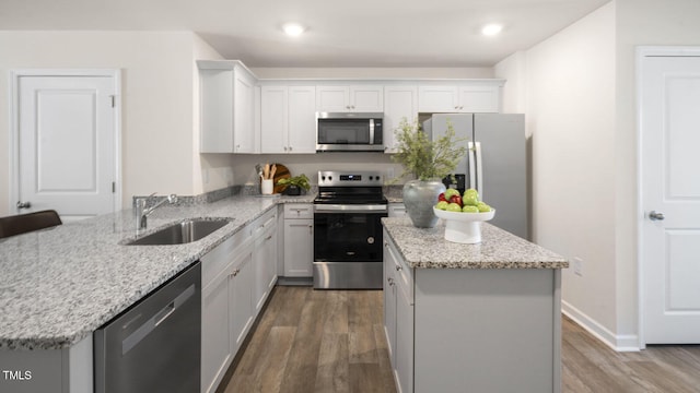 kitchen with stainless steel appliances, white cabinetry, sink, wood-type flooring, and a center island