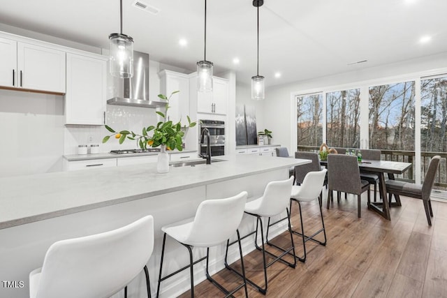 kitchen with white cabinets, pendant lighting, and light wood-type flooring