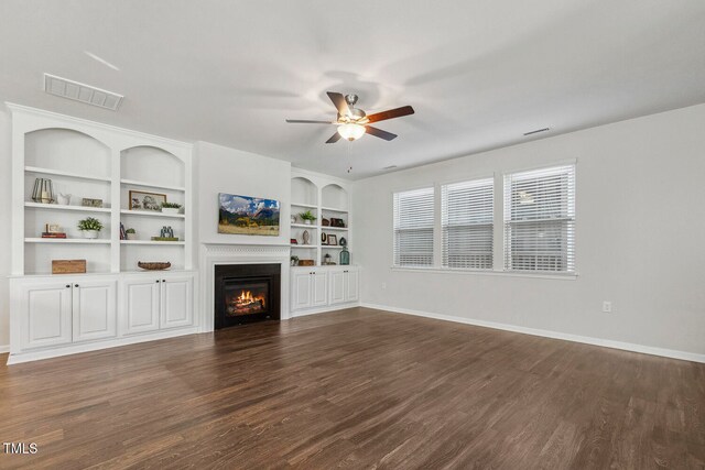 unfurnished living room with ceiling fan, dark hardwood / wood-style flooring, and built in shelves