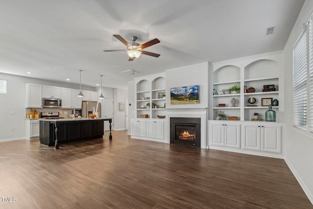 living room featuring ceiling fan, dark hardwood / wood-style flooring, and built in shelves