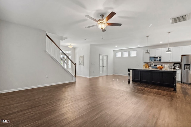 living room with ceiling fan, dark wood-type flooring, a healthy amount of sunlight, and sink