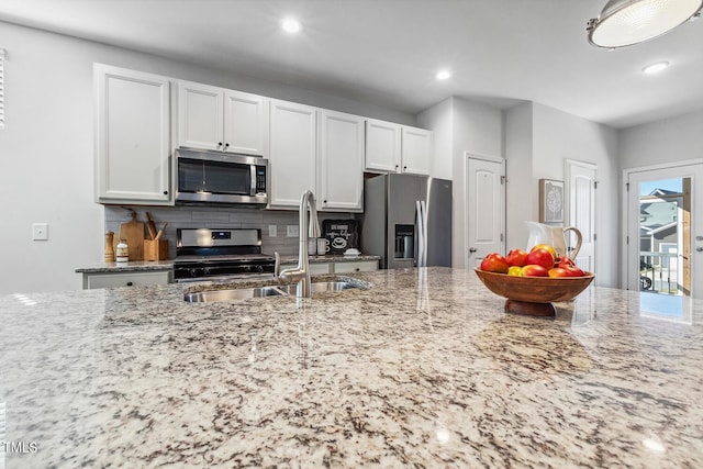 kitchen featuring light stone countertops, appliances with stainless steel finishes, and white cabinetry