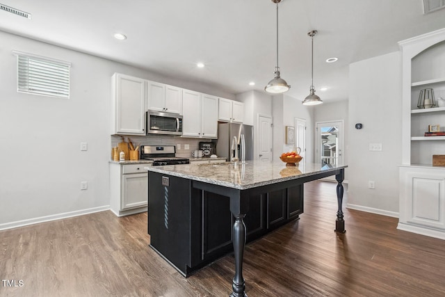 kitchen with a kitchen island with sink, white cabinets, light stone countertops, a kitchen bar, and stainless steel appliances