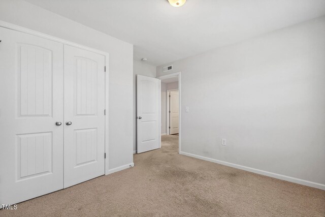 unfurnished bedroom featuring light carpet and a closet