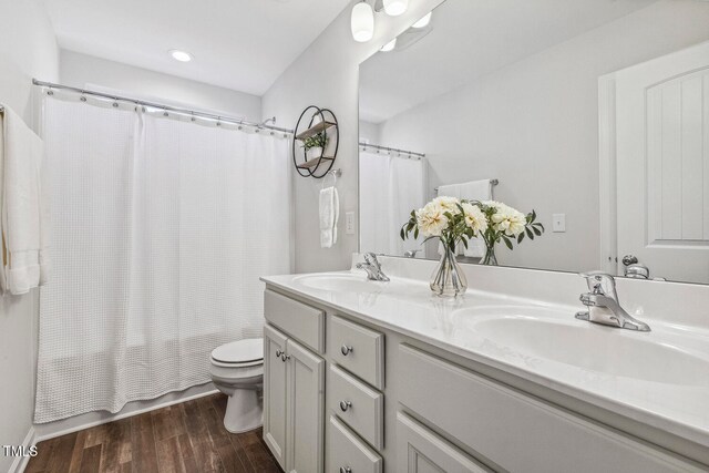 full bathroom with hardwood / wood-style flooring, vanity, toilet, and shower / tub combo with curtain