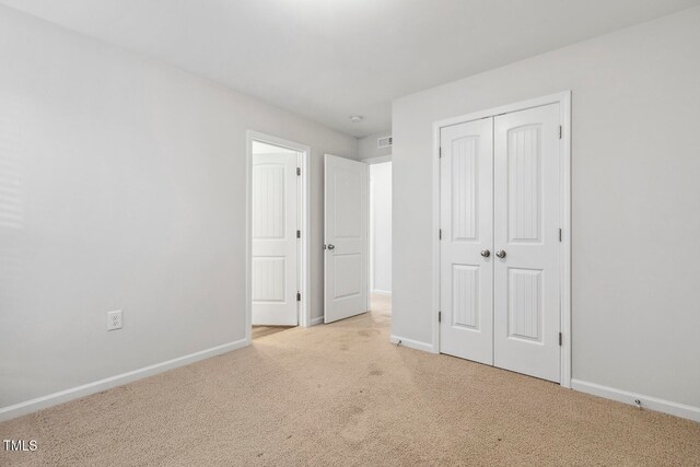 unfurnished bedroom featuring light carpet and a closet