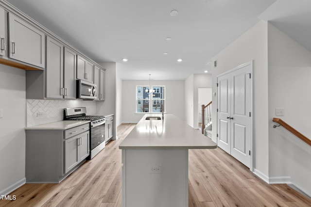 kitchen with stainless steel appliances, gray cabinets, and light hardwood / wood-style floors