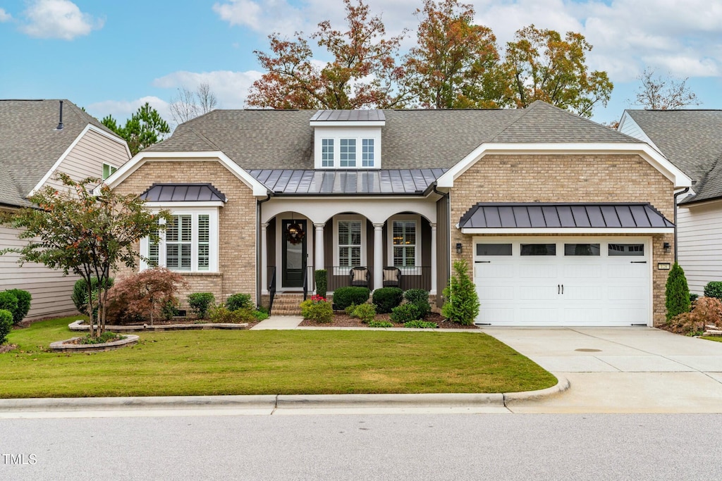 view of front of home with a garage, covered porch, and a front lawn