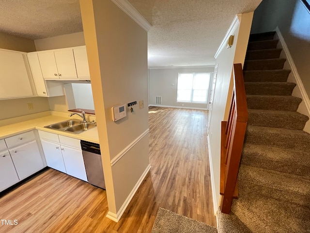 kitchen featuring sink, a textured ceiling, light hardwood / wood-style flooring, white cabinets, and dishwasher