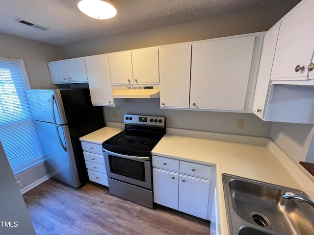 kitchen featuring stainless steel appliances, wood-type flooring, a textured ceiling, sink, and white cabinetry