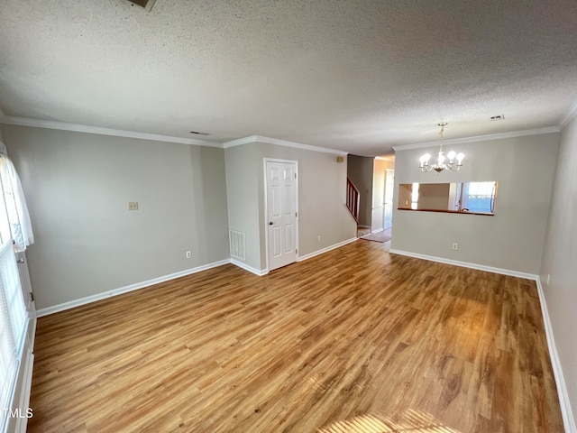 spare room featuring hardwood / wood-style flooring, a chandelier, a textured ceiling, and crown molding