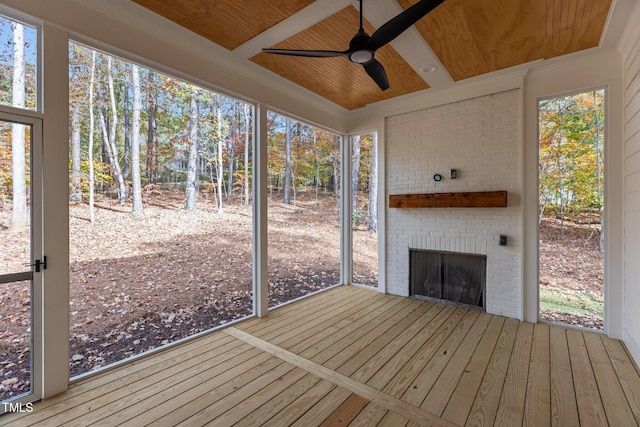 unfurnished sunroom with a fireplace, ceiling fan, and wood ceiling