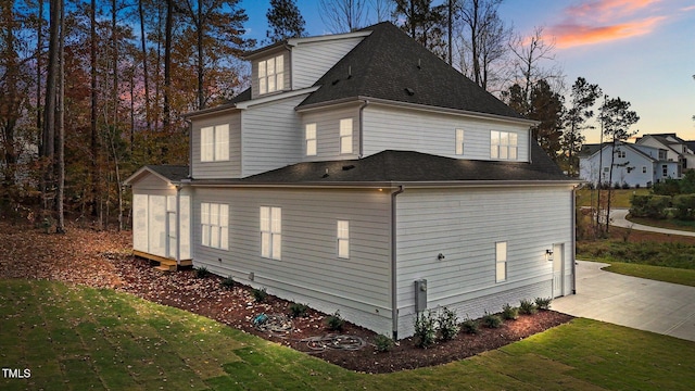 property exterior at dusk featuring a lawn and a patio area