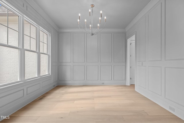 unfurnished dining area with ornamental molding, an inviting chandelier, and light hardwood / wood-style flooring