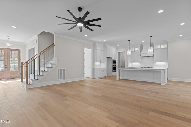 unfurnished living room with french doors, light hardwood / wood-style floors, sink, ornamental molding, and ceiling fan