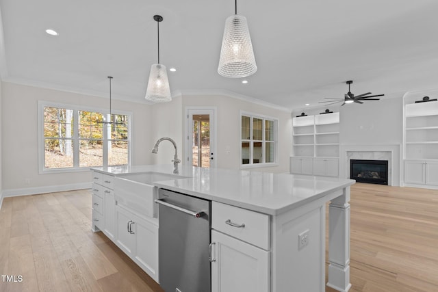 kitchen with white cabinets, light hardwood / wood-style flooring, decorative light fixtures, and an island with sink