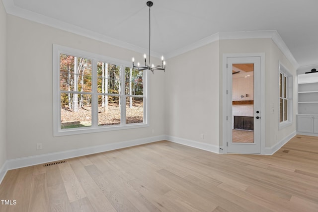 unfurnished dining area featuring ornamental molding, light wood-type flooring, and a notable chandelier