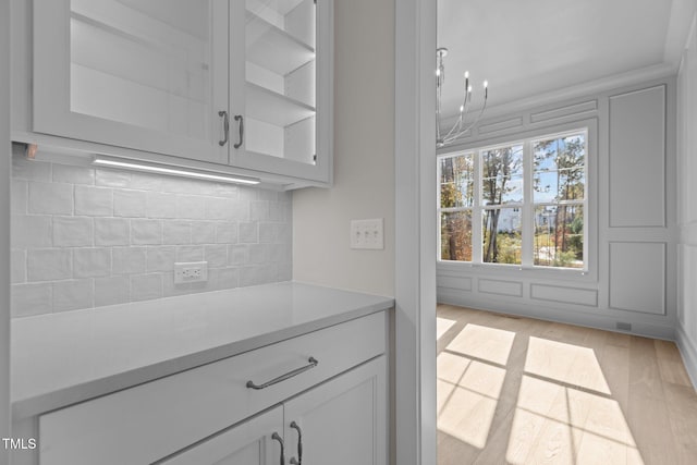 kitchen with backsplash, light hardwood / wood-style flooring, and a notable chandelier